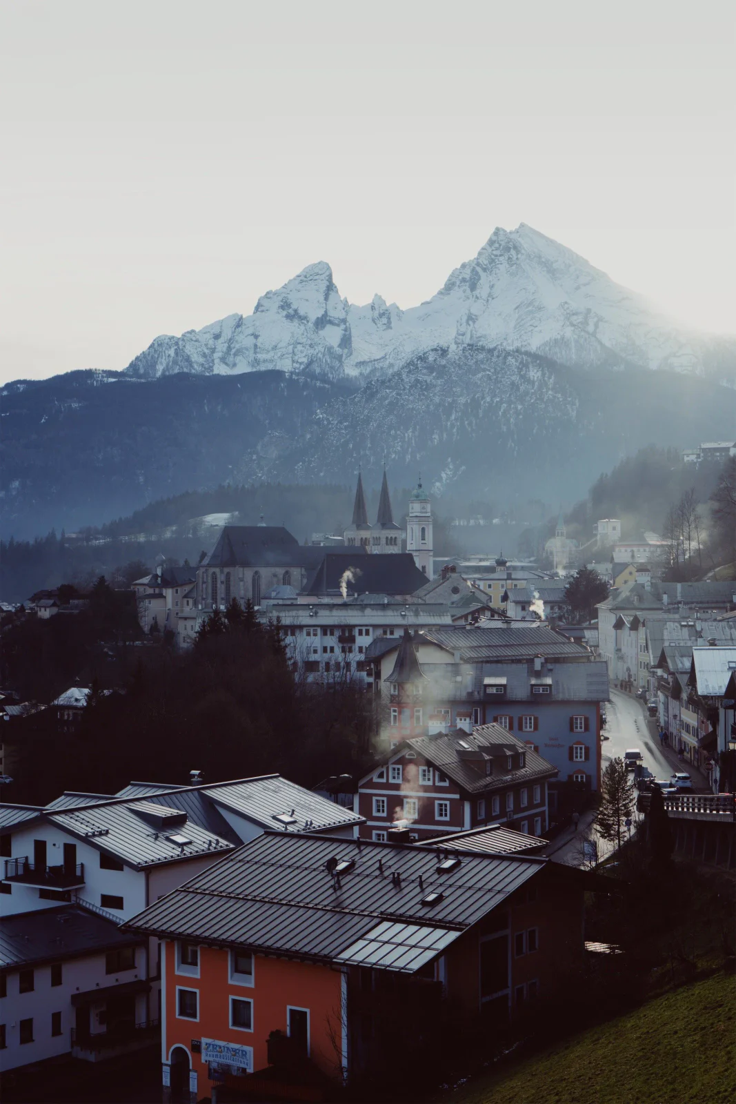 Historische Stadt vor einem verschneiten Bergmassiv im Winterlicht