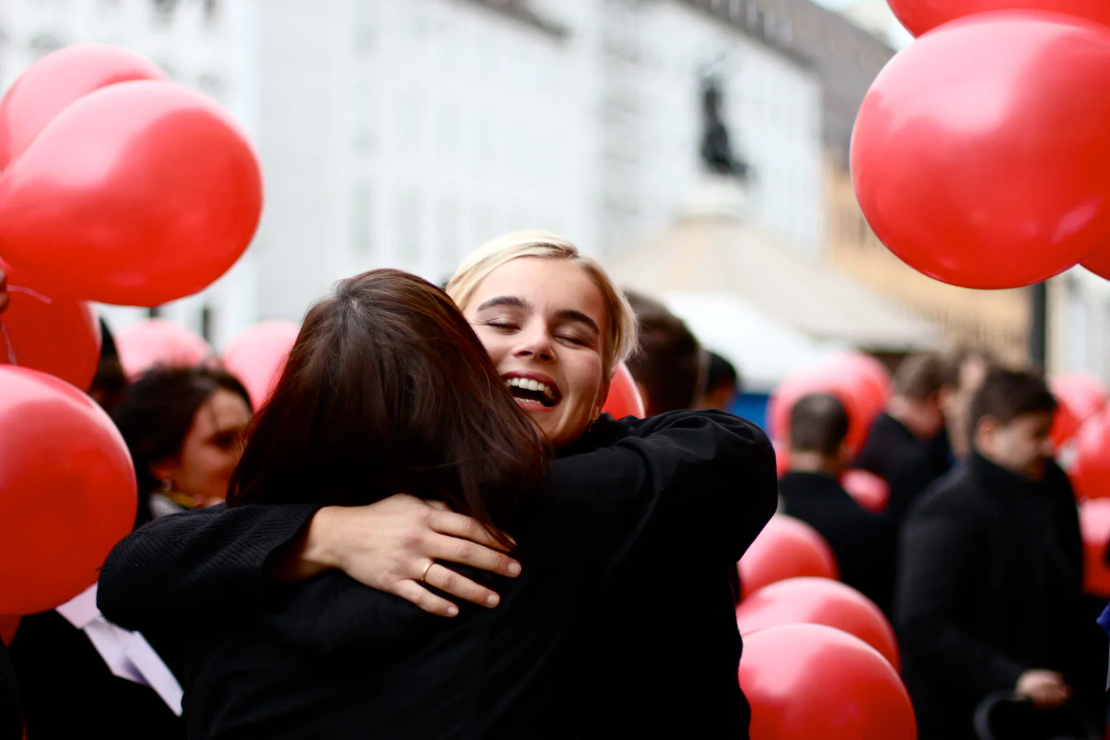 Emotionale Umarmung bei einer Feier mit roten Herzballons
