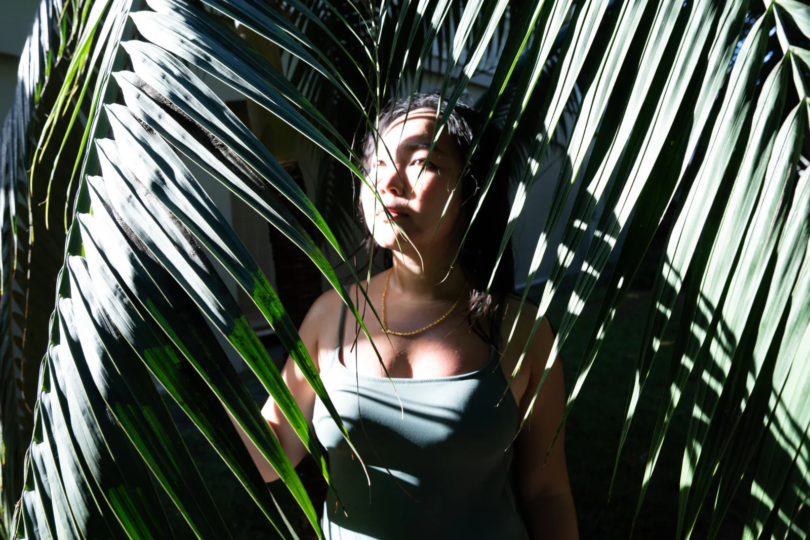 Natürliches Frauenportrait im Sonnenlicht zwischen Palmenblättern