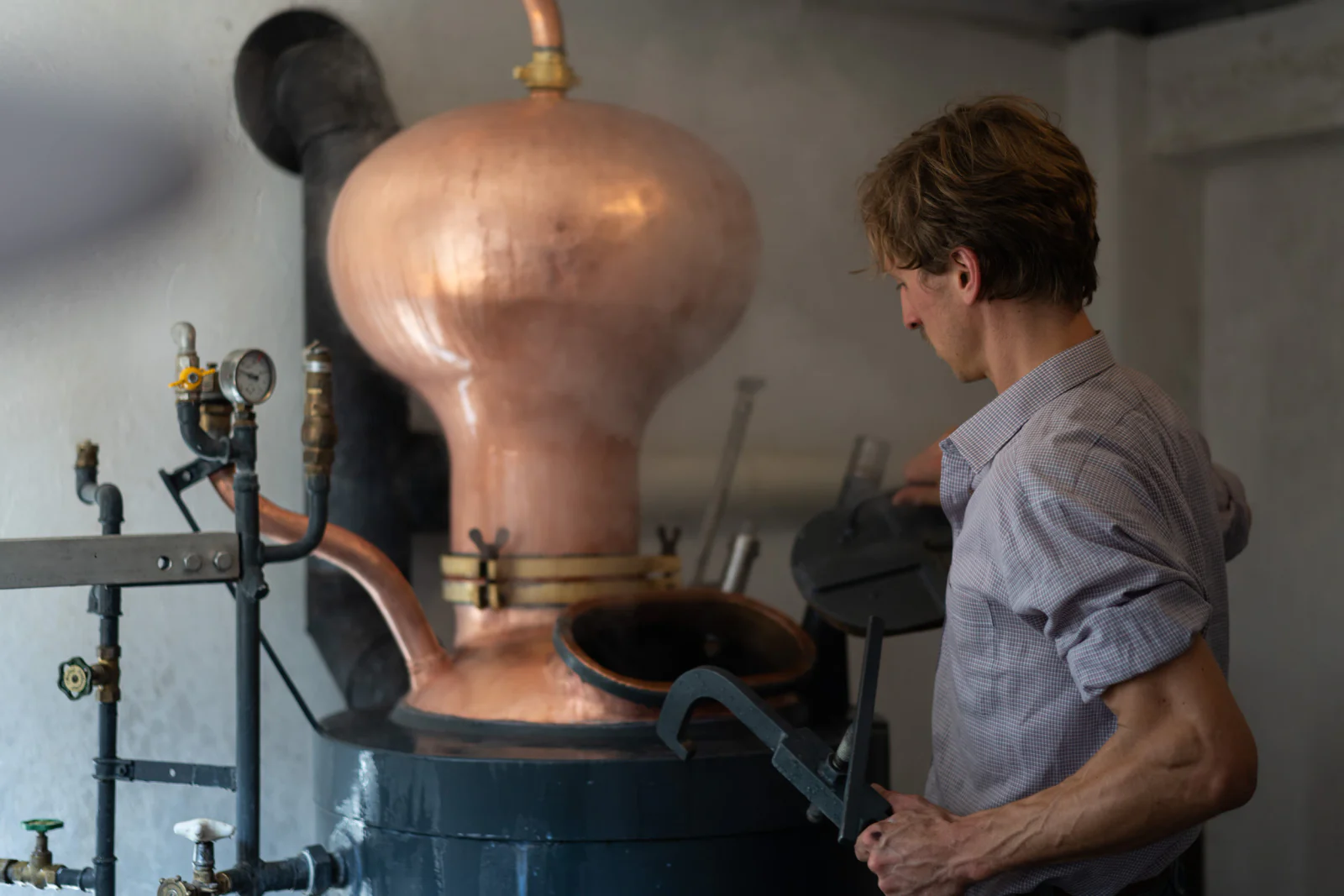 Brennmeister öffnet den Kupferkessel in der Destillerie Kolonko